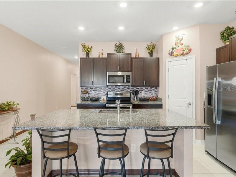 3943 Resting Robin Avenue Bartow, FL 33830 - Photo 8 of 38 a kitchen with stainless steel appliances granite countertop a table and chairs in it