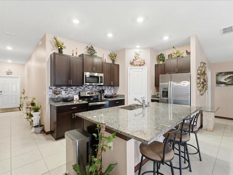3943 Resting Robin Avenue Bartow, FL 33830 - Photo 9 of 38 a kitchen with stainless steel appliances kitchen island granite countertop a table chairs and a refrigerator