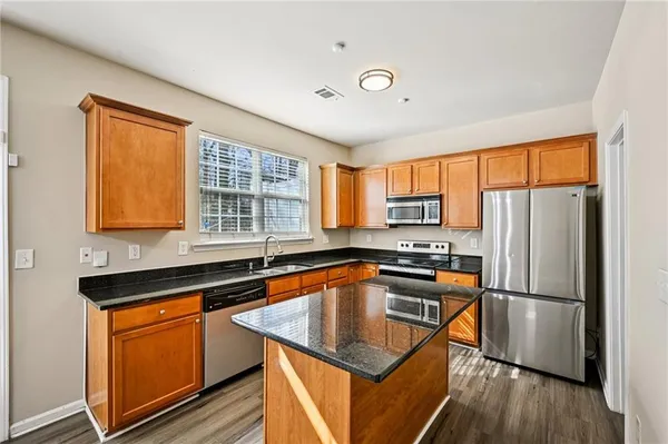 a kitchen that has a sink a microwave a refrigerator and wooden floor