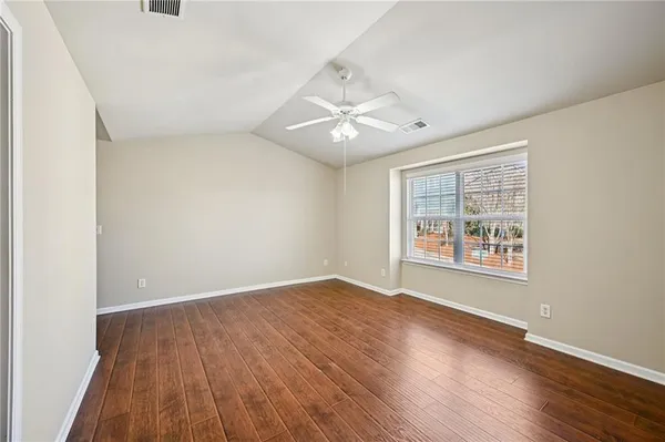an empty room with wooden floor and windows