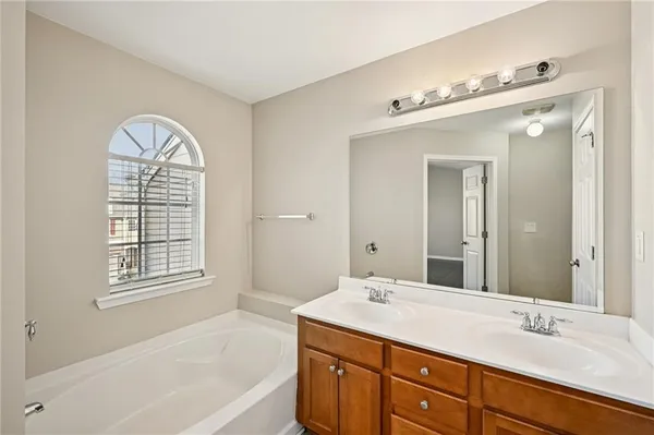 a bathroom with a sink double vanity granite tub and a mirror