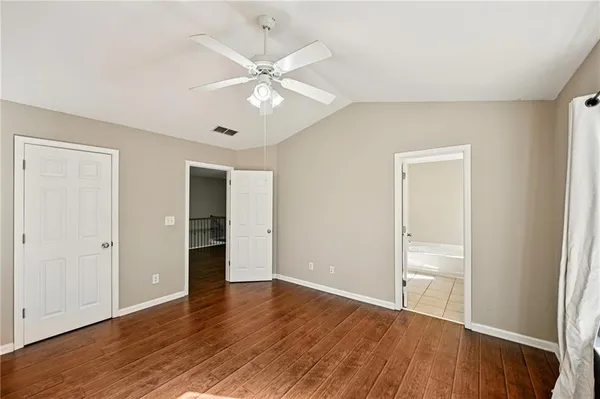 an empty room with wooden floor and ceiling fan