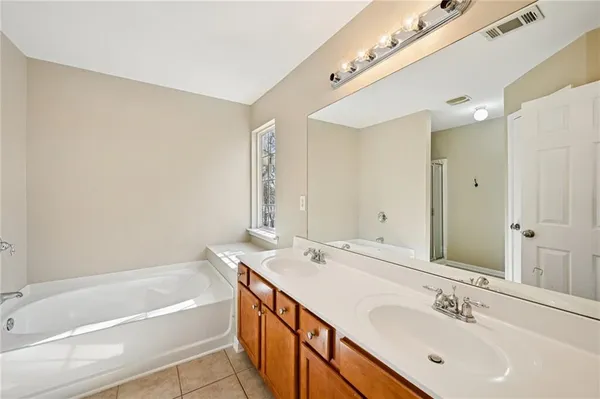 a bathroom with a tub double sink and mirror