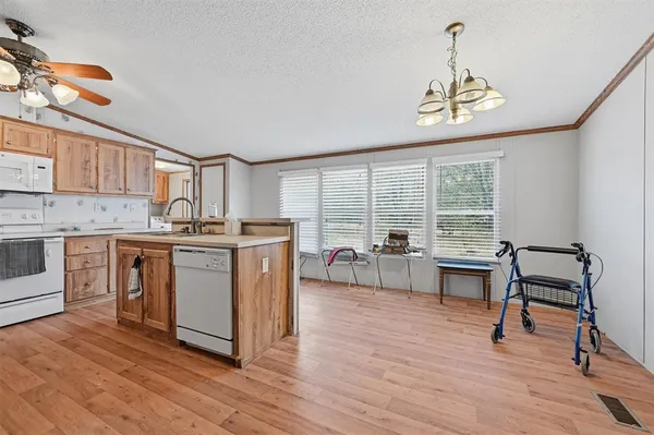 a kitchen with stainless steel appliances granite countertop a stove top oven a chimney cabinets and wooden floor