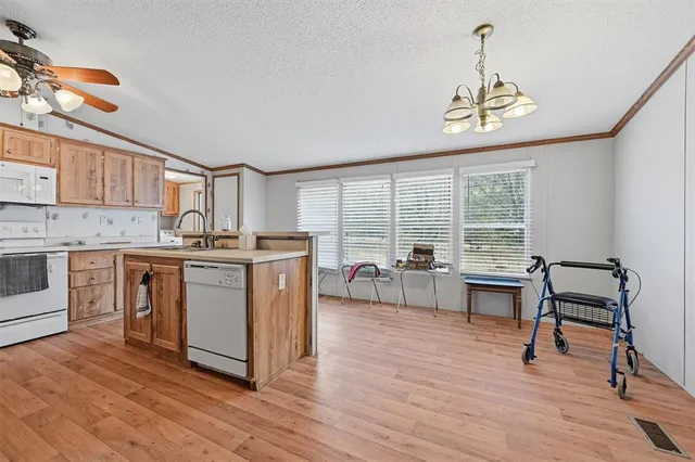 a kitchen with stainless steel appliances granite countertop a stove top oven a chimney cabinets and wooden floor