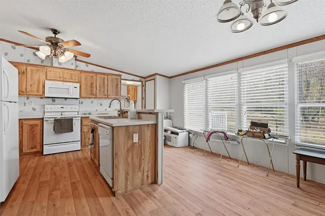 a kitchen with a refrigerator a stove top oven a sink and cabinets with wooden floor