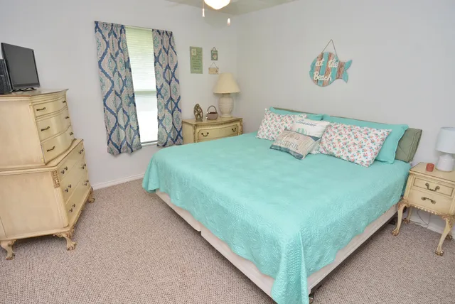 a bedroom with a bed and a flat tv screen on dresser
