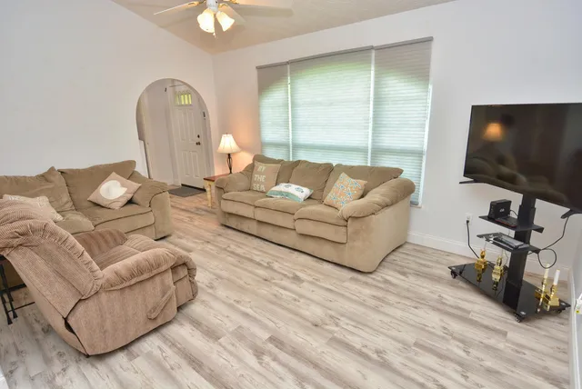 a living room with furniture a flat screen tv and a large window