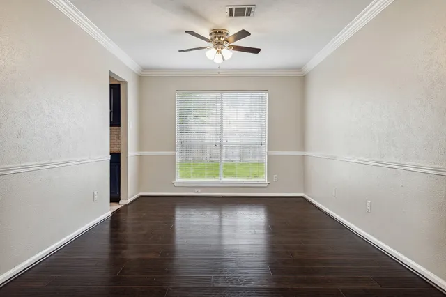 an empty room with wooden floor fireplace and windows