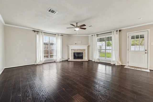 an empty room with wooden floor fireplace and windows