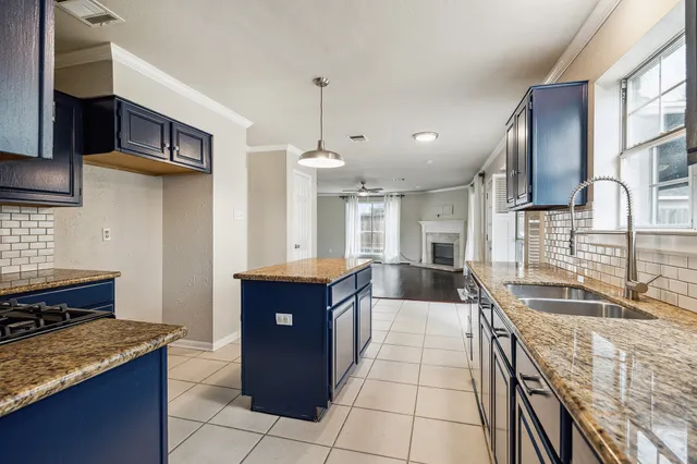 a kitchen with stainless steel appliances kitchen island granite countertop a refrigerator a stove top oven a sink dishwasher and wooden cabinets with large window