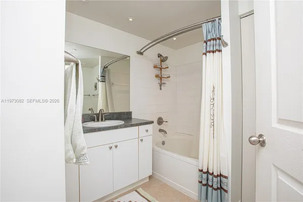 a bathroom with a granite countertop sink a mirror a vanity and a bathtub