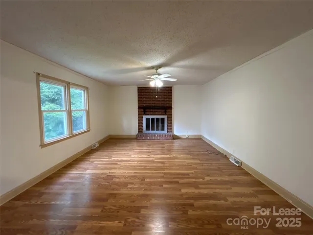 a view of an empty room with window and wooden floor