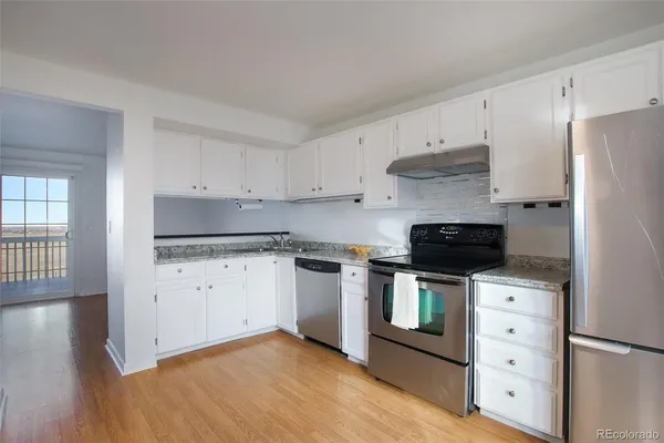a kitchen with stainless steel appliances white cabinets and a stove top oven