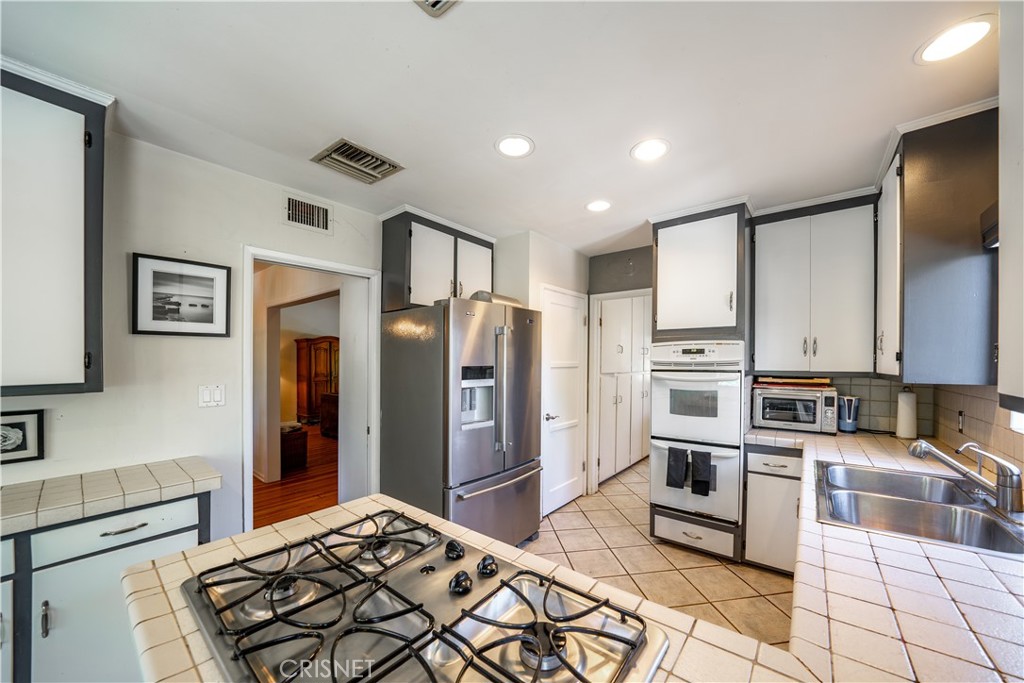 3667 Willowcrest Avenue Studio City, CA 91604 - Photo 11 of 49 a kitchen with stainless steel appliances kitchen island granite countertop a refrigerator and a stove top oven