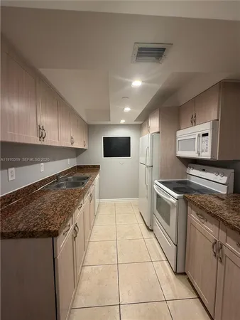 a large kitchen with stainless steel appliances granite countertop a stove a sink and a refrigerator