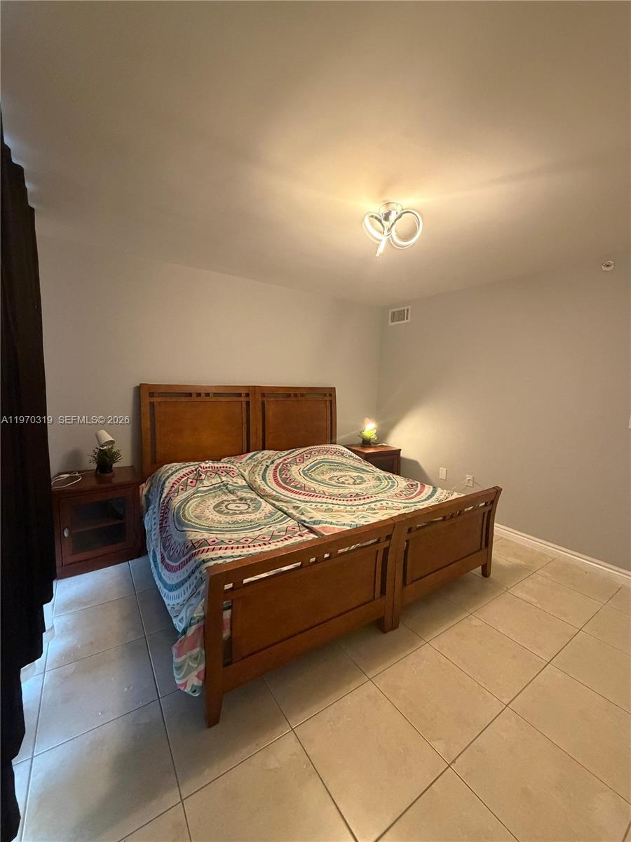 17600 North Bay Road, Unit N907 Sunny Isles Beach, FL 33160 - Photo 16 of 22 a bedroom with a bed and a lamp on table