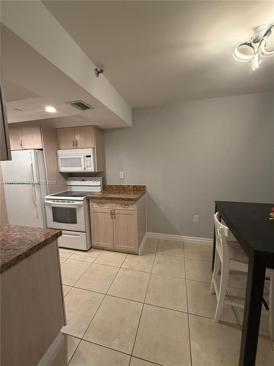 17600 North Bay Road, Unit N907 Sunny Isles Beach, FL 33160 - Photo 2 of 22 a kitchen with a sink a stove top oven and stainless steel appliances