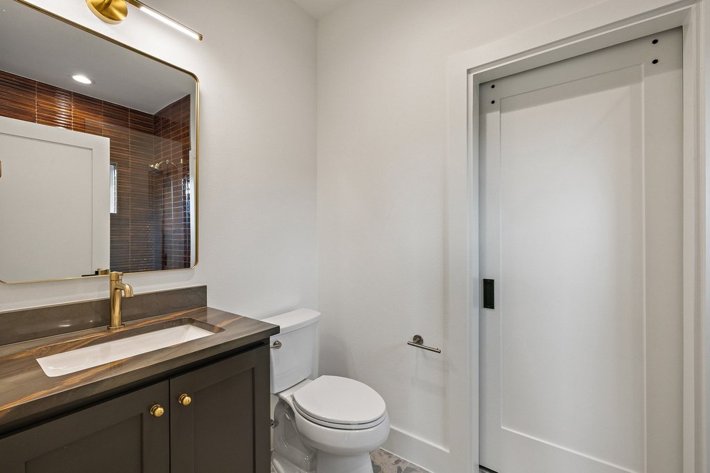 9207 Zyle Road Austin, TX 78737 - Photo 26 of 40 A well-appointed bathroom offers contemporary fixtures and a rich, tiled shower enclosure visible in the mirror's reflection.
