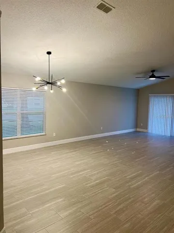 an empty room with wooden floor fan and window
