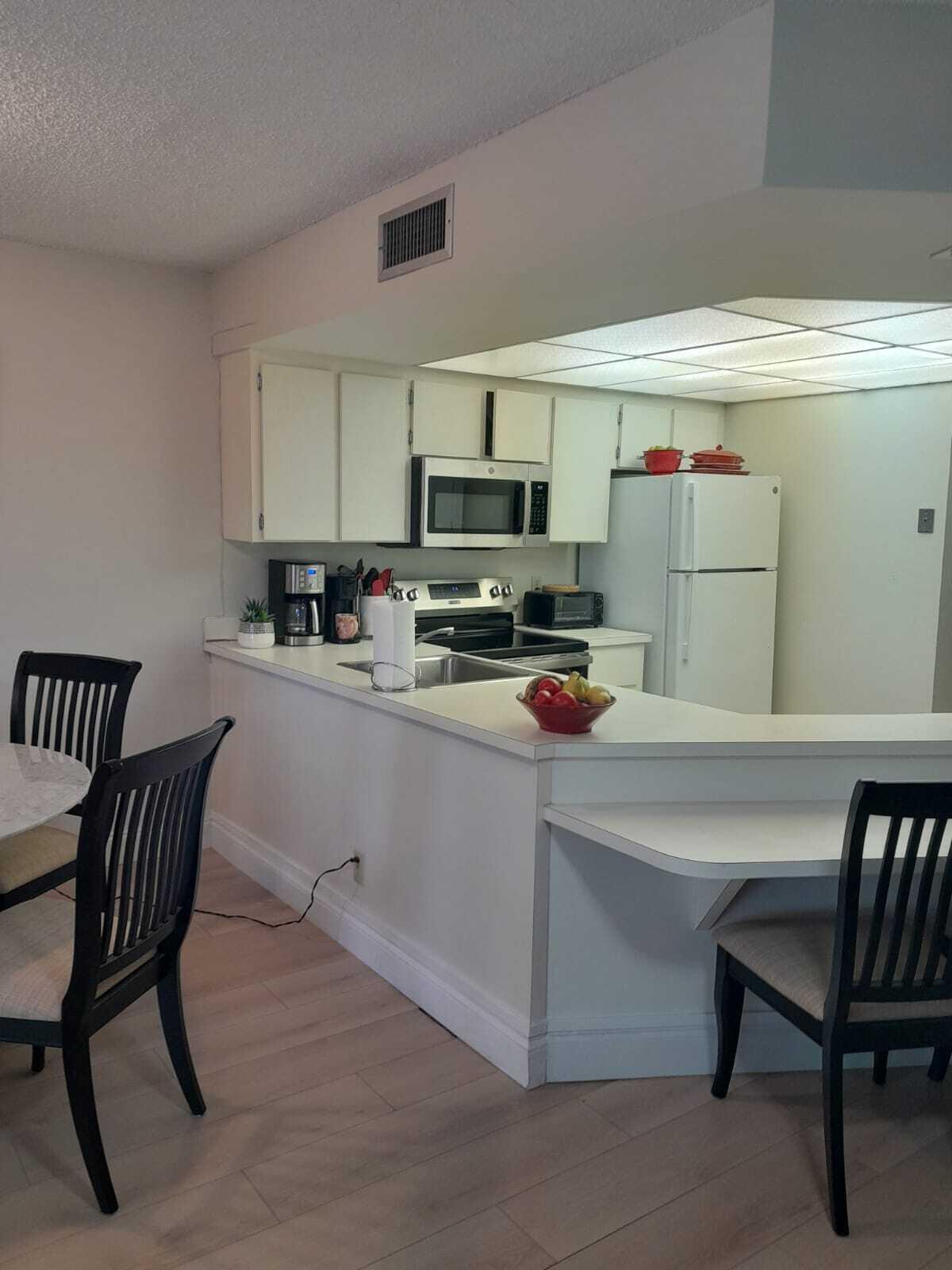 1605 Highway 1, Unit C302 Jupiter, FL 33477 - Photo 11 of 30 a kitchen with a dining table chairs and a refrigerator