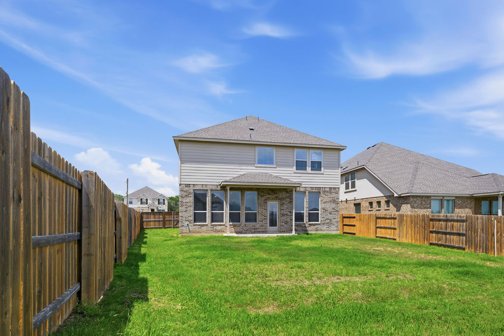 1005 Ridge Runner Drive Georgetown, TX 78628 - Photo 30 of 32 Expansive backyard featuring a manicured lawn, a full wood privacy fence, and a two-story residence with a covered patio