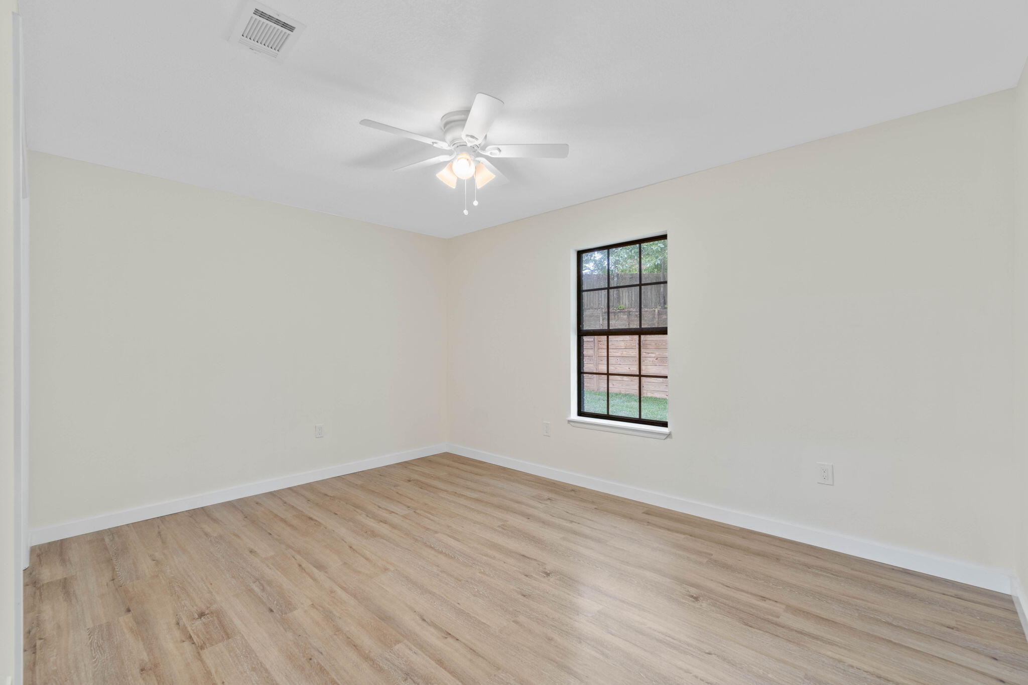 2313 Canal Drive Niceville, FL 32578 - Photo 31 of 52 an empty room with wooden floor fan and windows