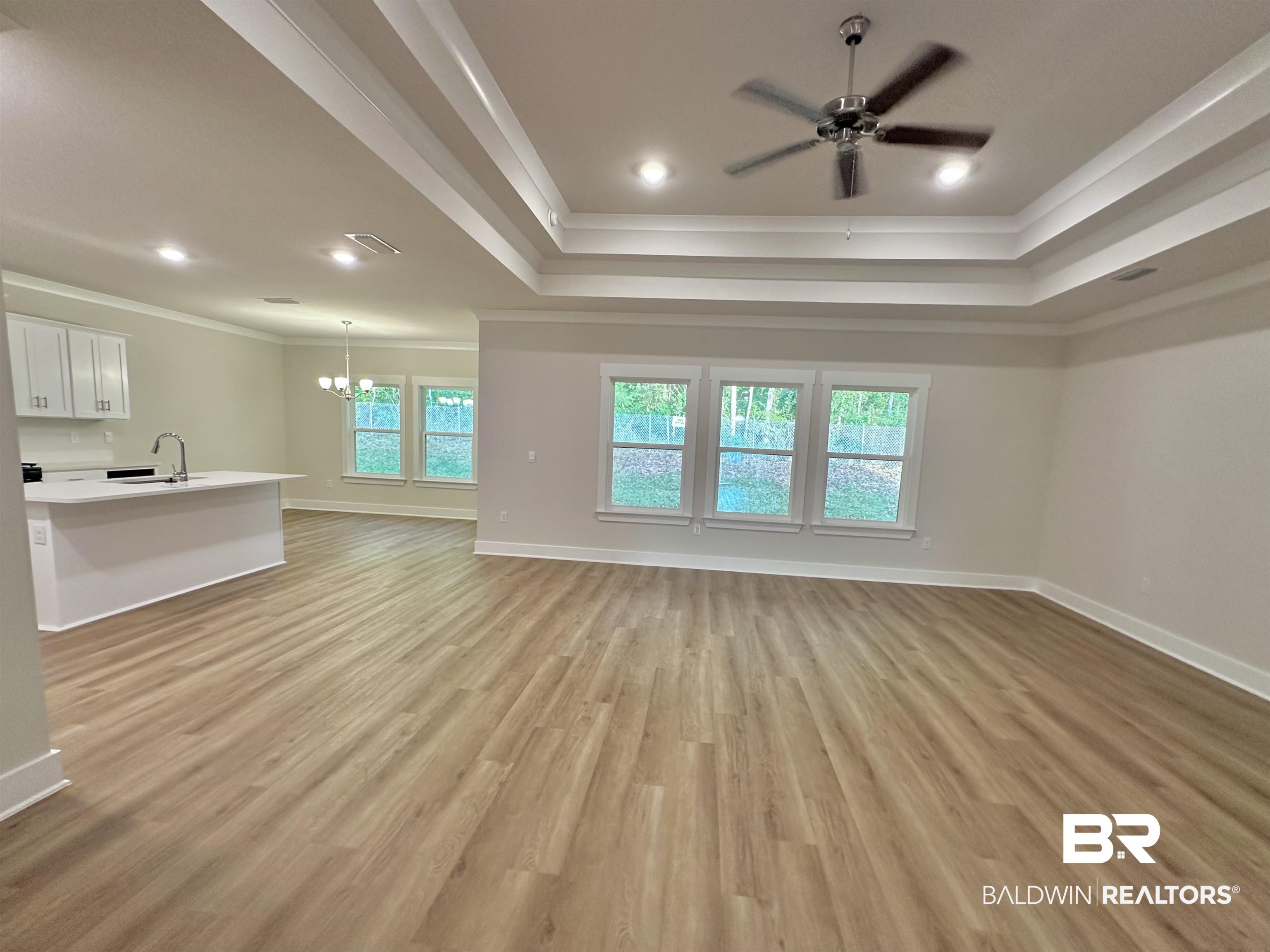 342 Barndling Street Fairhope, AL 36532 - Photo 12 of 50 Unfurnished living room with light hardwood / wood-style flooring, a raised ceiling, sink, and crown molding