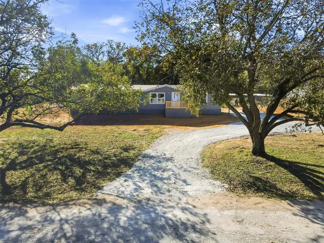 a front view of a house with a yard covered with snow and trees
