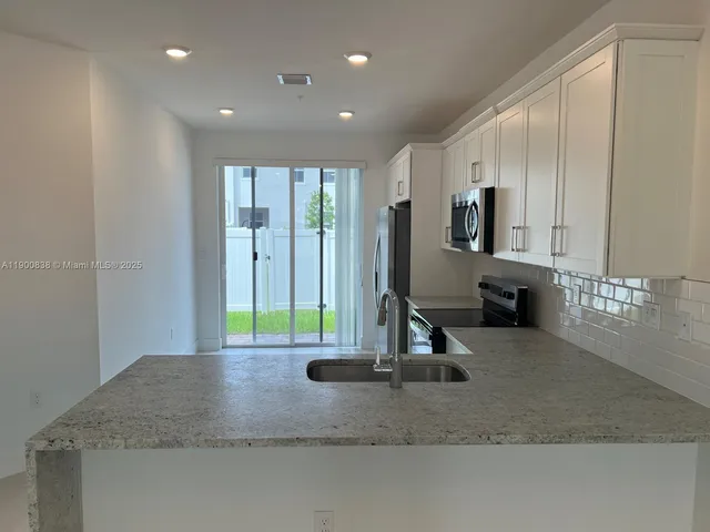 a kitchen with stainless steel appliances granite countertop a stove a sink and a microwave