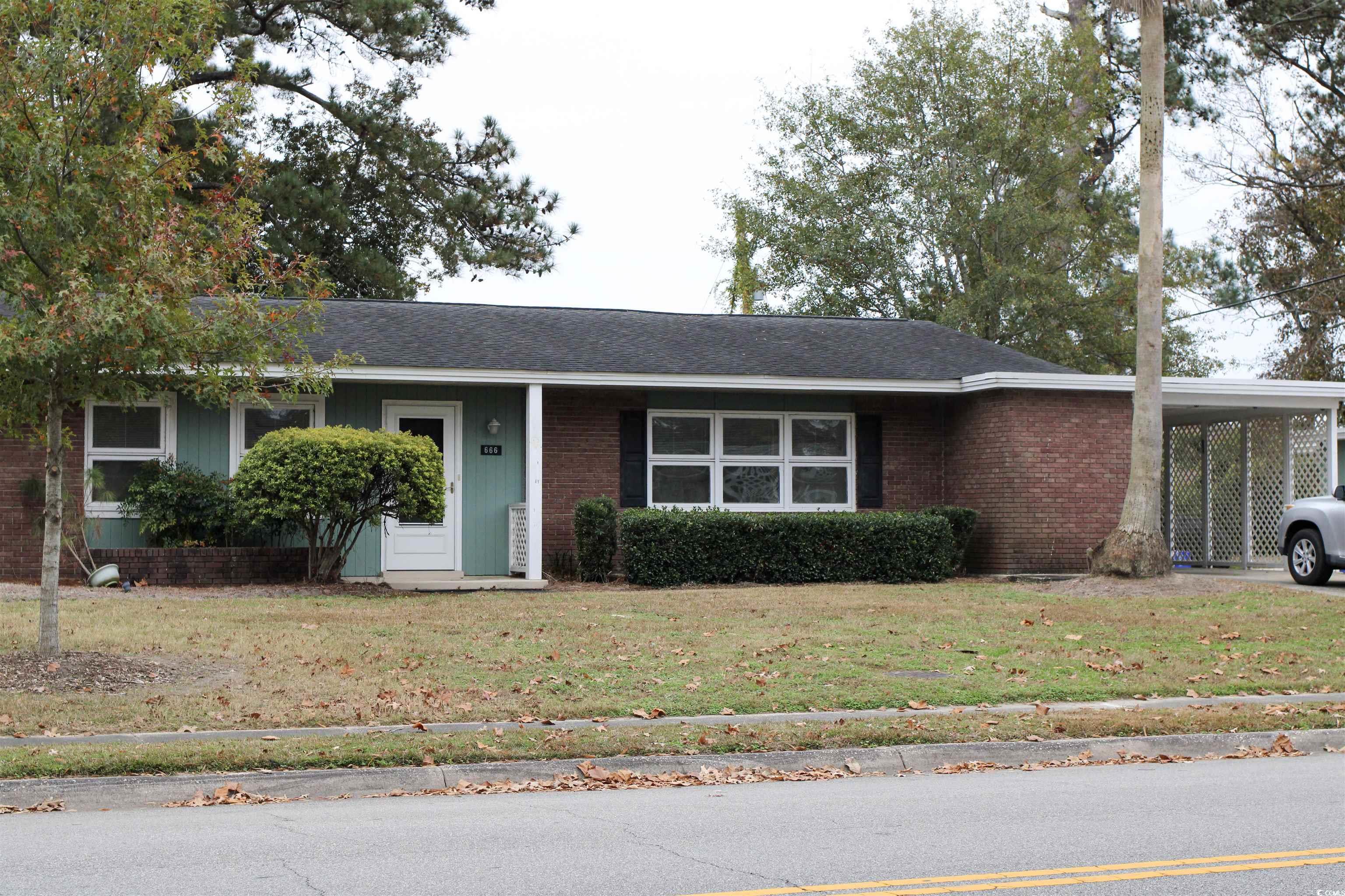 Duplex/condo with a carport, a front lawn, brick siding, and a shingled roof