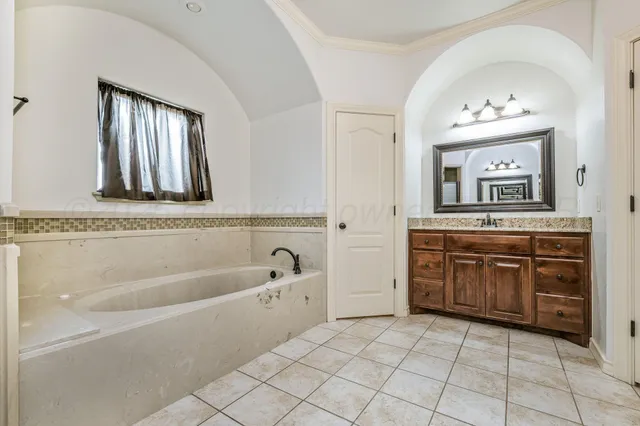 a spacious bathroom with a tub sink and mirror