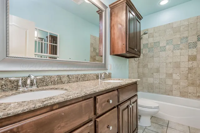 a bathroom with a granite countertop sink a toilet and mirror