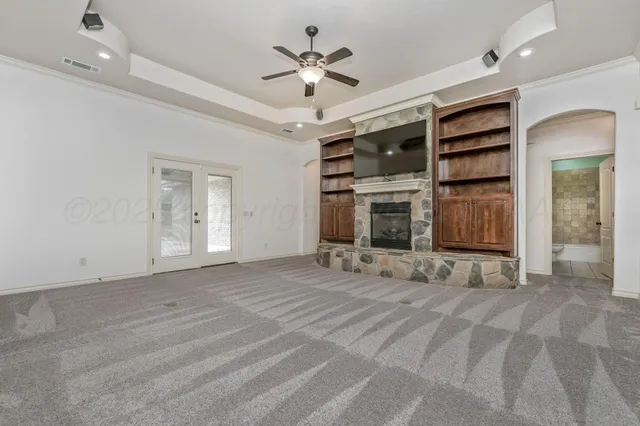 a view of an empty room with a fireplace and a ceiling fan