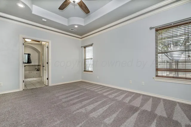an empty room with chandelier fan and windows