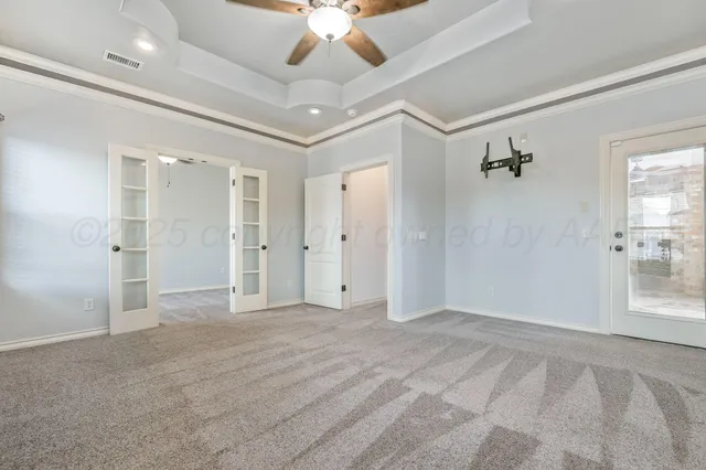 a view of an empty room with a chandelier fan and windows