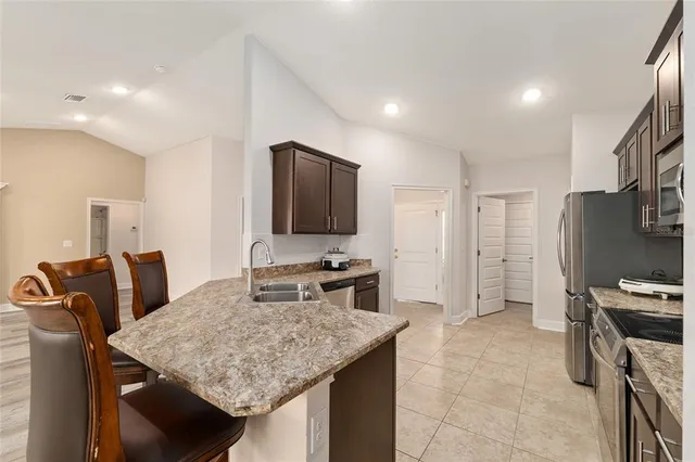 a kitchen with stainless steel appliances granite countertop a stove top oven a refrigerator and a sink