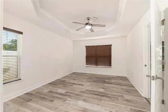 an empty room with wooden floor and windows