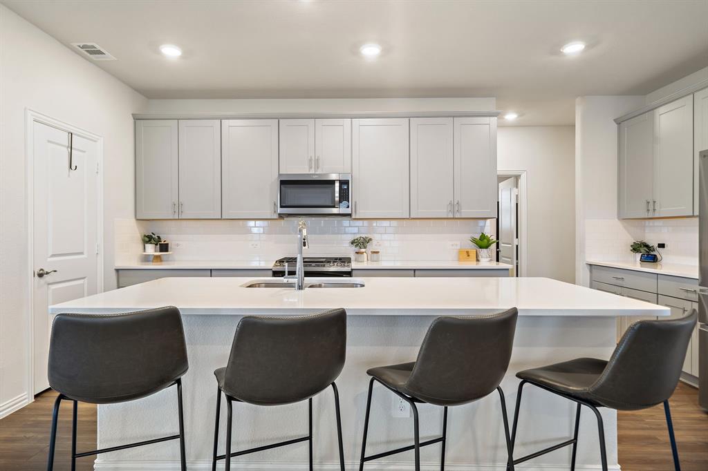 2232 Sun Star Drive Haslet, TX 76052 - Photo 8 of 40 a white kitchen with a stove a sink a microwave a dining table and chairs
