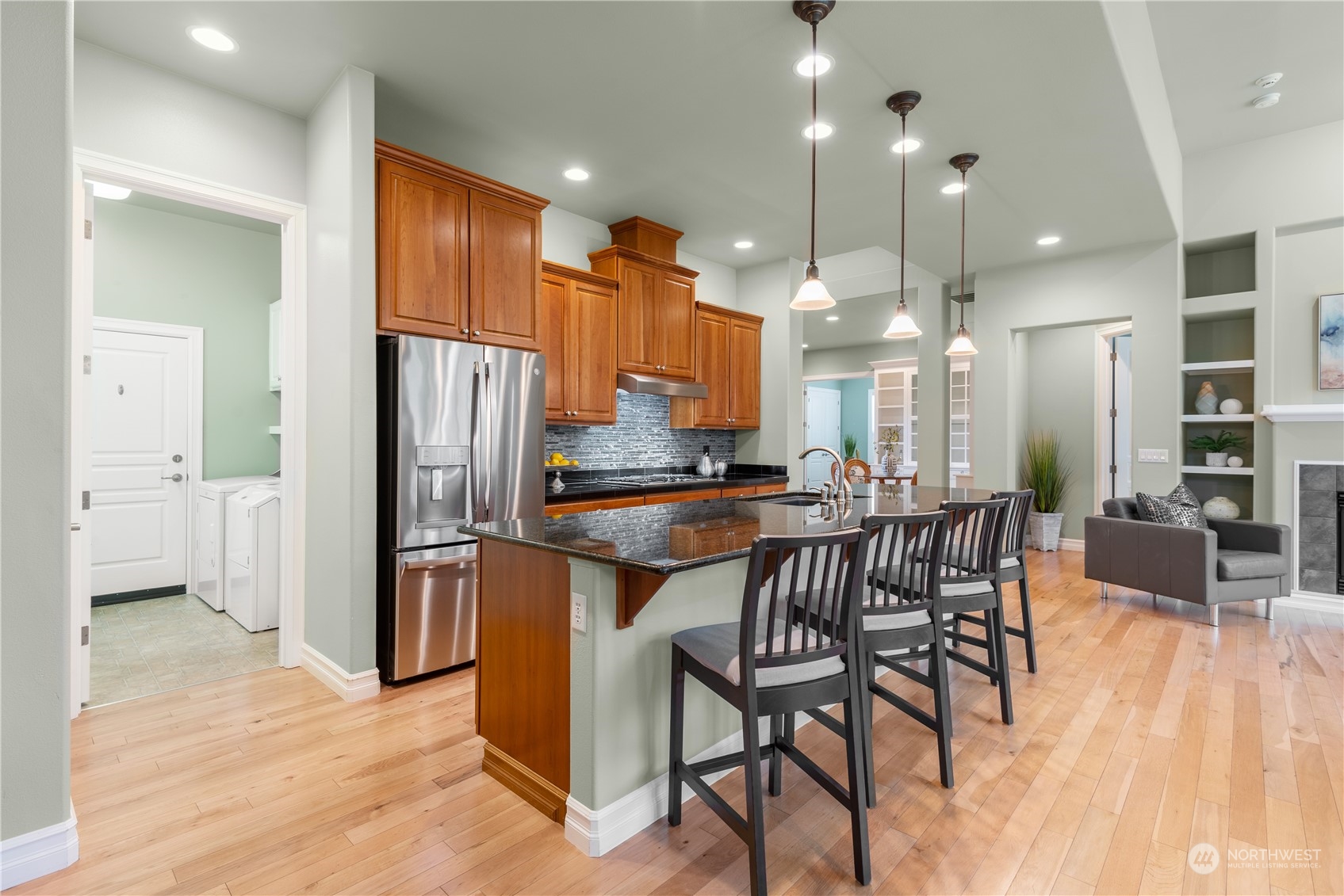 23923 Northeast Adair Road Redmond, WA 98053 - Photo 9 of 38 a kitchen with stainless steel appliances kitchen island granite countertop a refrigerator a stove a sink a dining table and chairs with wooden floor