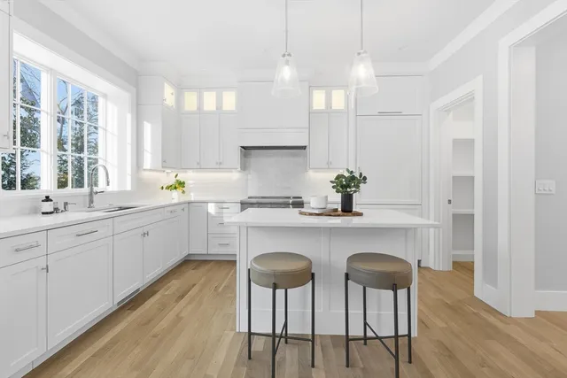 a white kitchen with wooden floor and chairs