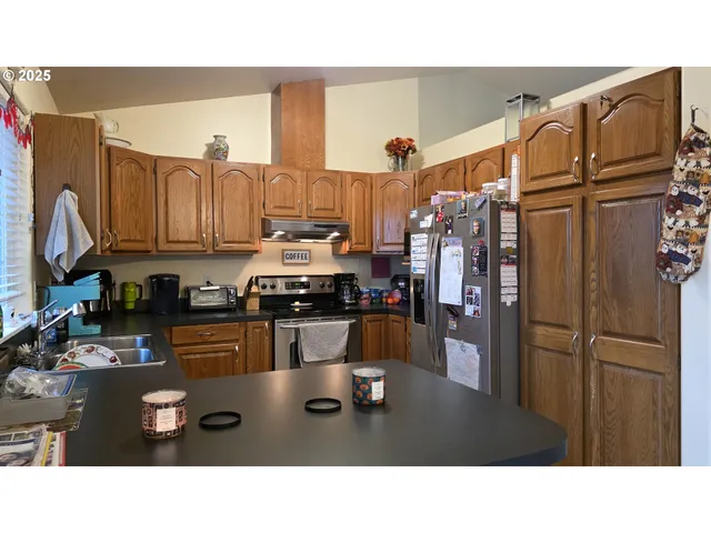 a kitchen with stainless steel appliances kitchen island granite countertop a refrigerator and cabinets