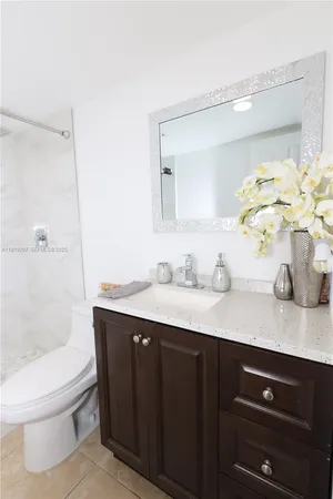 a bathroom with a granite countertop sink a toilet and a mirror