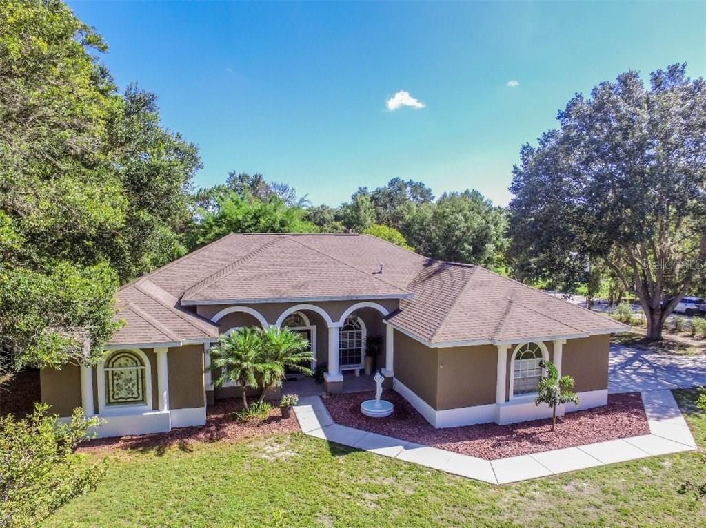 a aerial view of a house with table and chairs under an umbrella