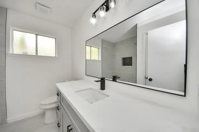 a bathroom with a sink a toilet and mirror