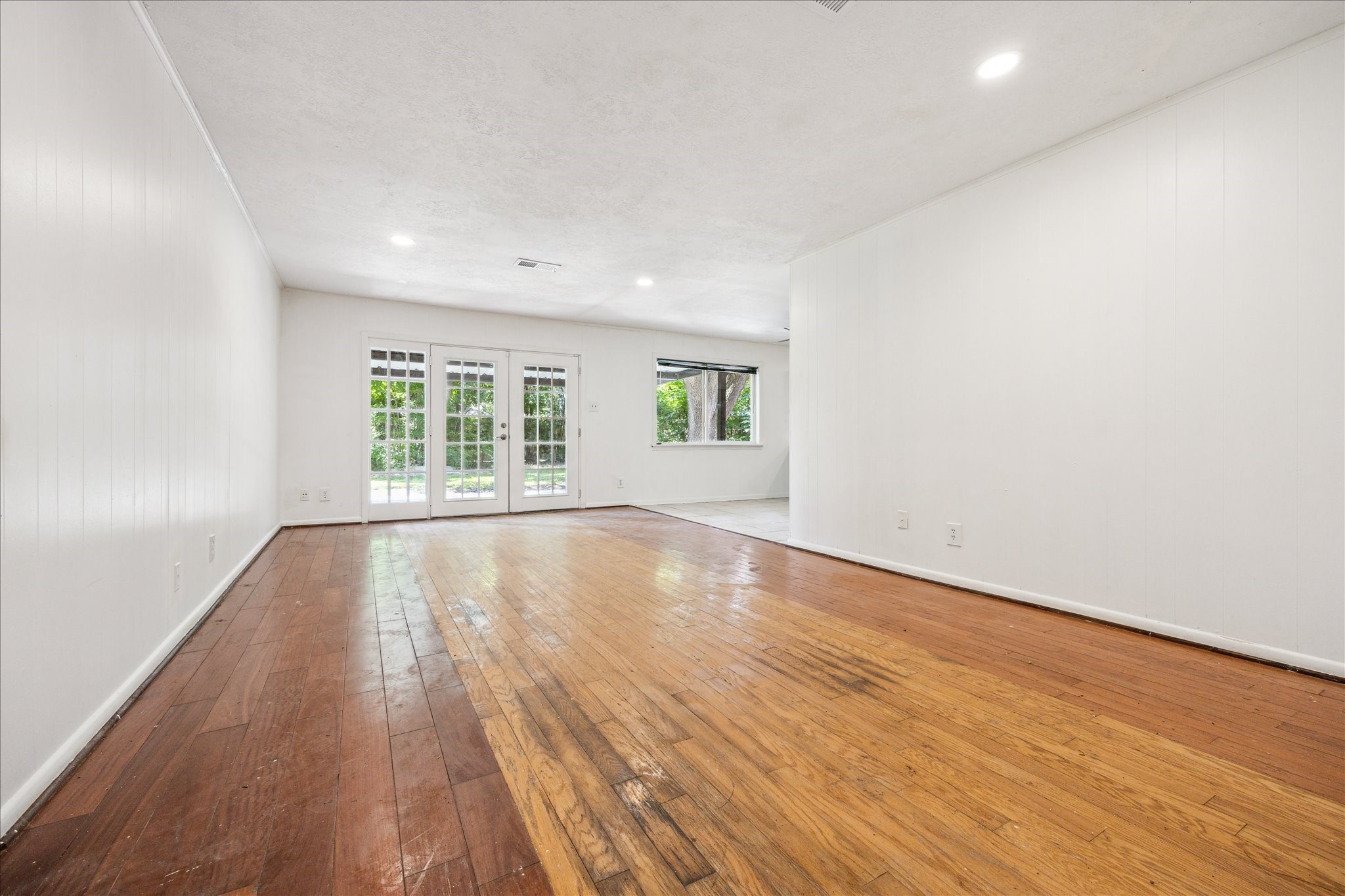 5419 Beechnut Street Houston, TX 77096 - Photo 8 of 28 Expansive den with wood flooring, recessed lighting, and French doors to the backyard, offering natural light and open flow into the breakfast area and kitchen.