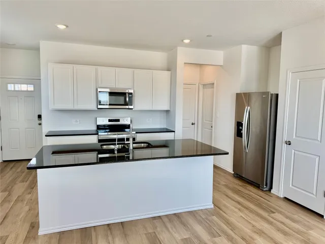 a kitchen with stainless steel appliances granite countertop a refrigerator and a stove top oven