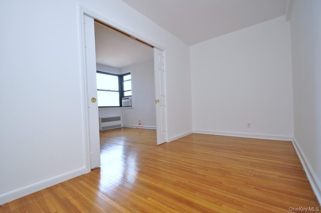 142 Garth Road, Unit 4A Scarsdale, NY 10583 - Photo 15 of 44 a view of an empty room with wooden floor and a window
