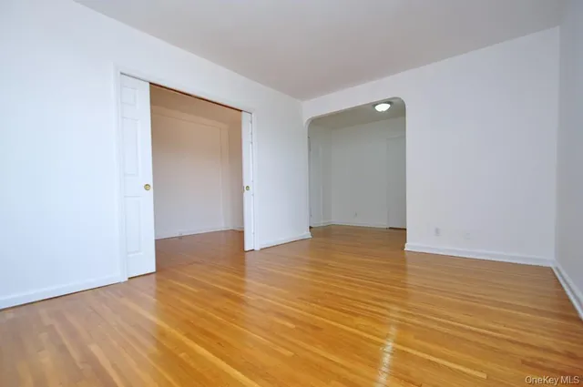 a view of an empty room with wooden floor and closet