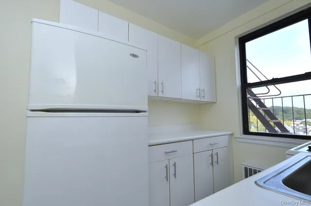 a kitchen with white cabinets and window